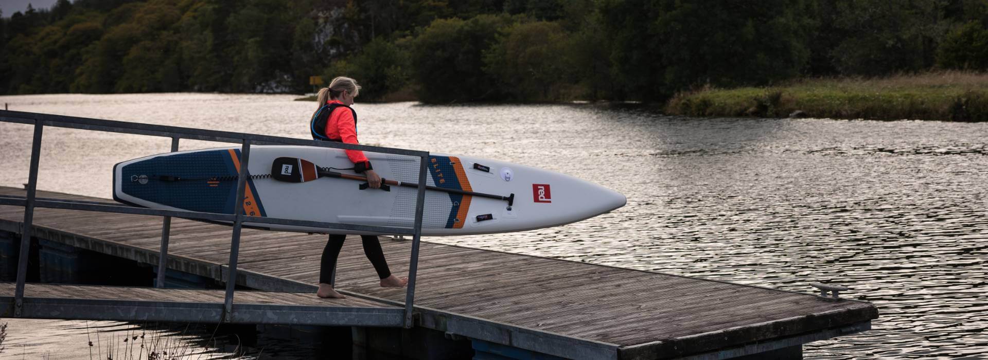 woman entering the water with elite racing paddle board
