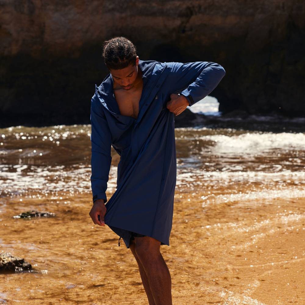 A man on the beach wearing a navy pursuit lightweight changing robe