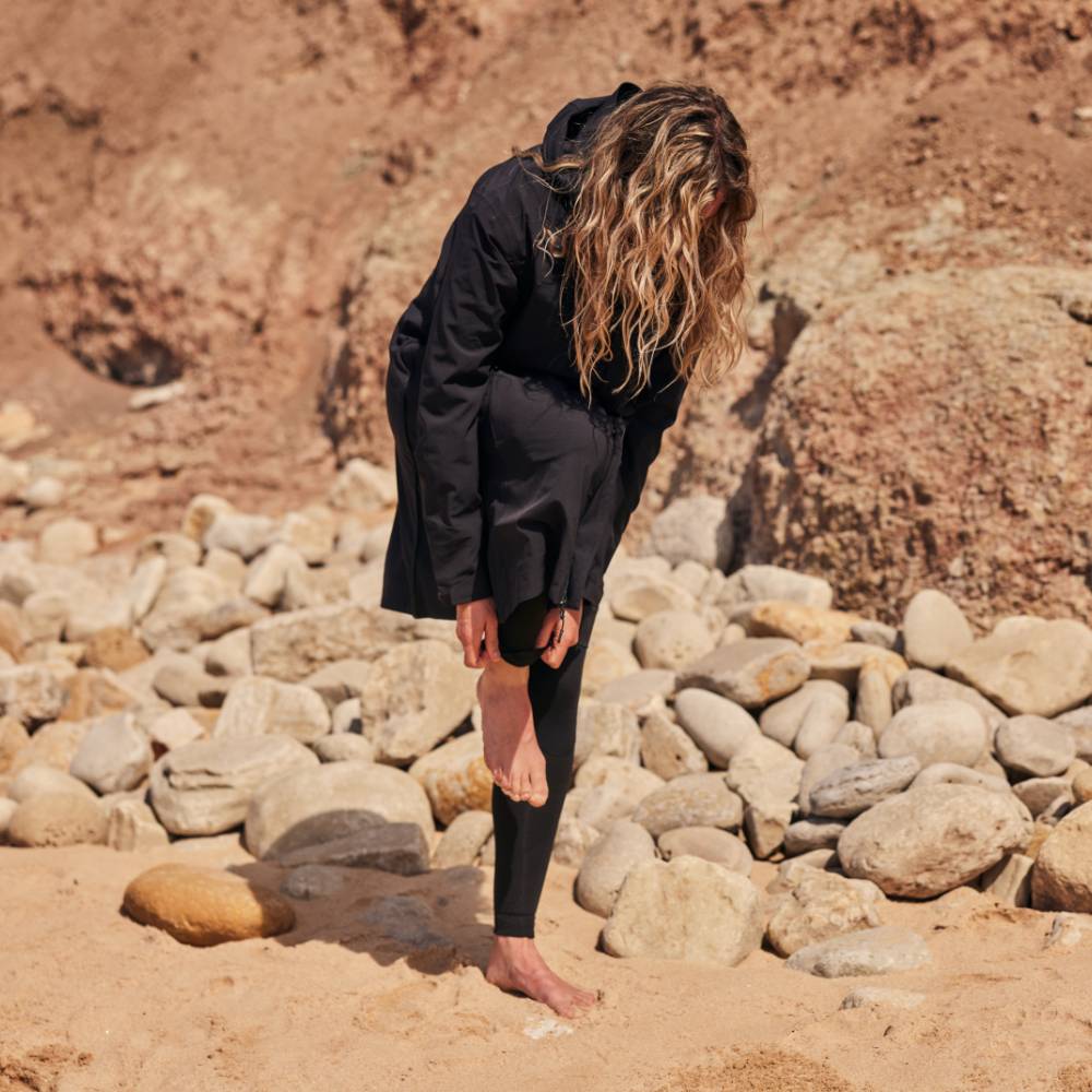 A woman changing in her black pursuit robe on the beach