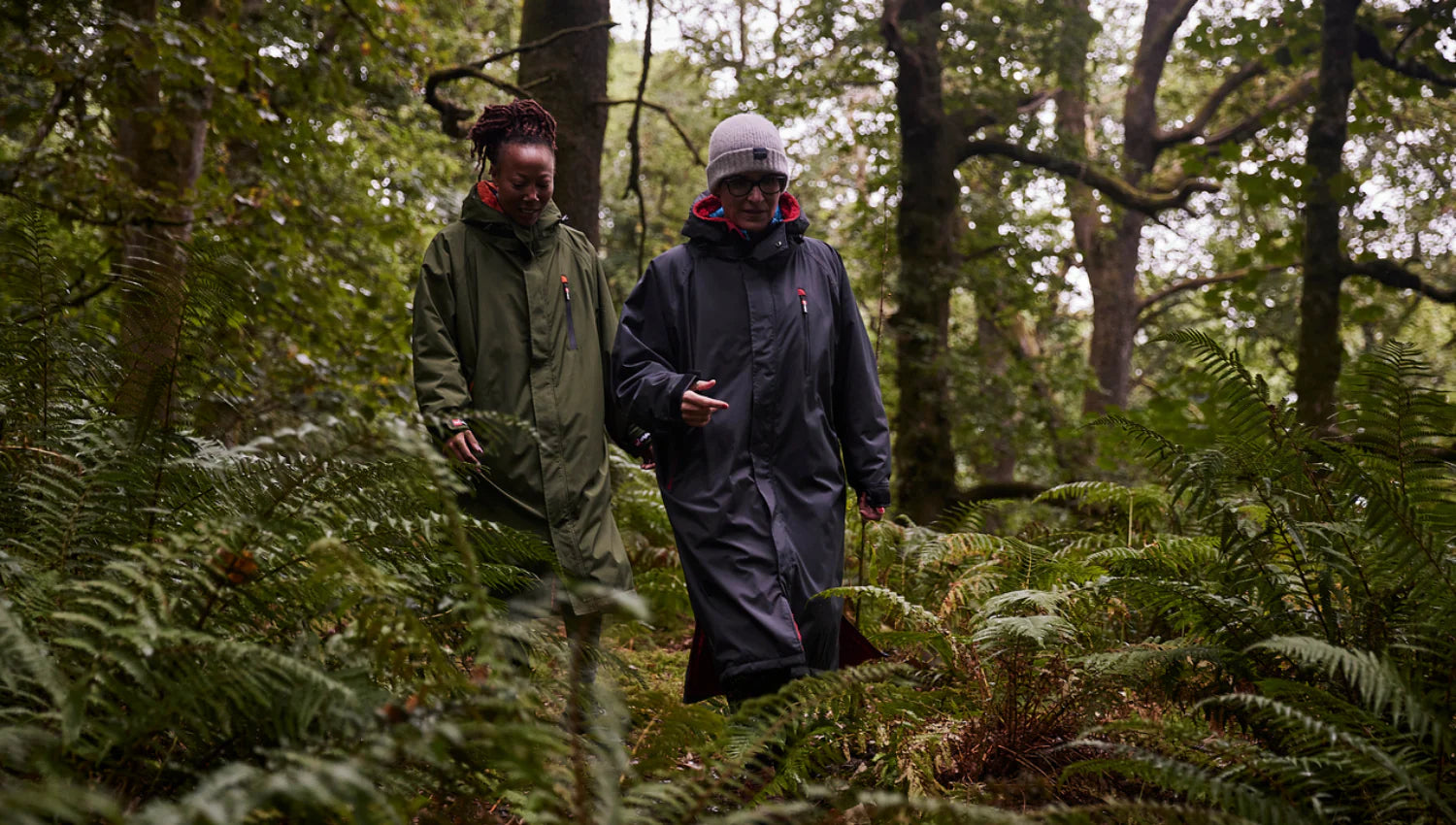 2 people wearing the Red Pro Change Robe whilst walking in the forest