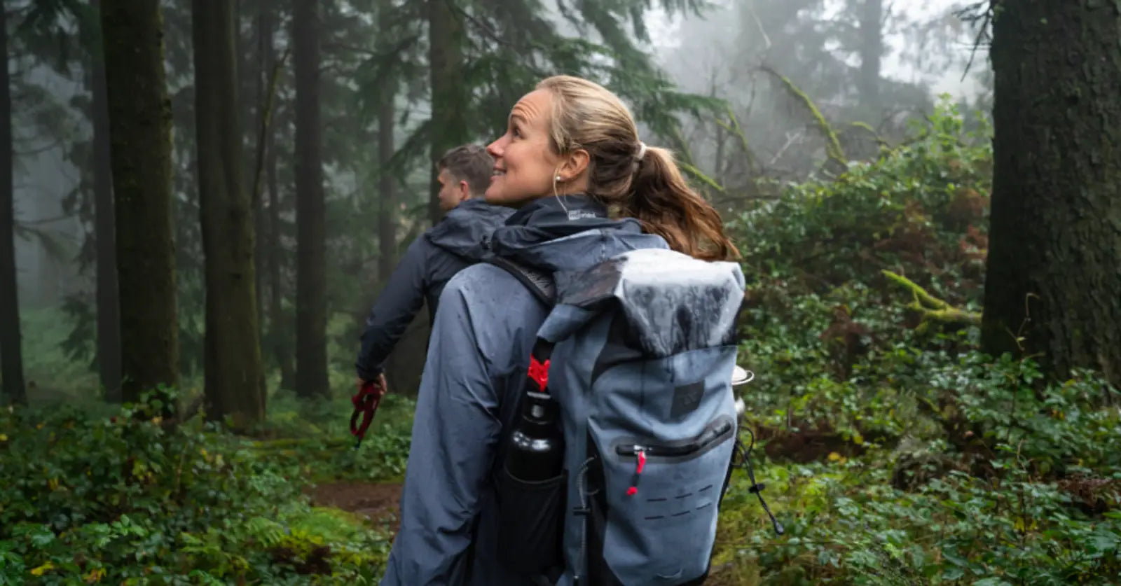 A woman walking through the forest looking at the trees