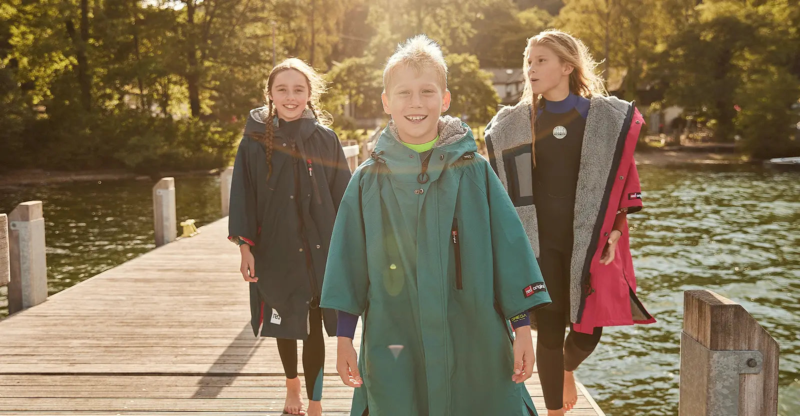 3 children wearing Red's Kids Changing Robes walking along a pier