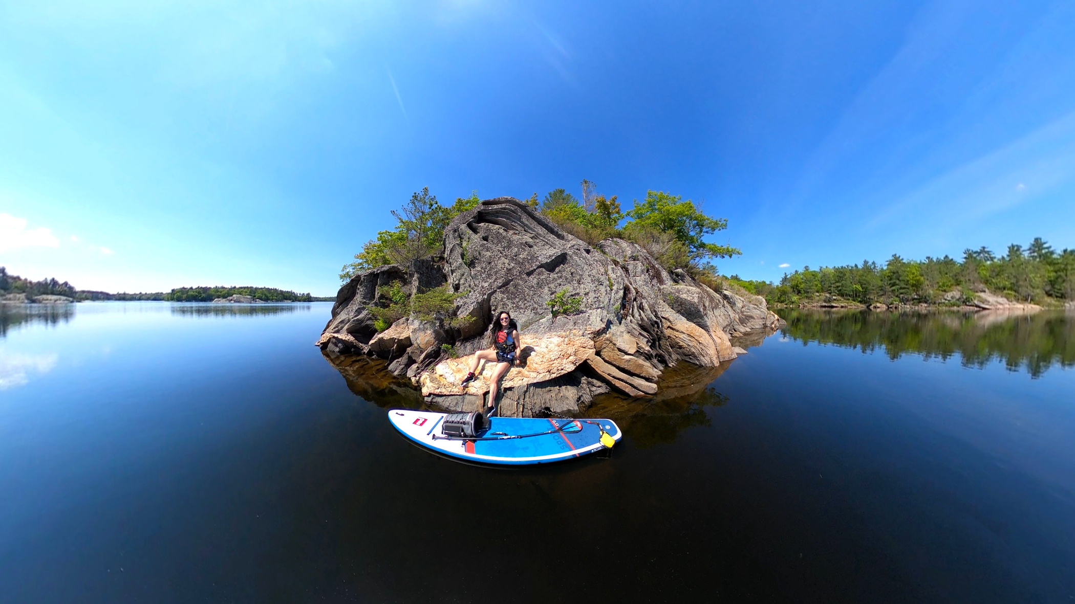 Woman sat on rocks on a lake with Red Original 