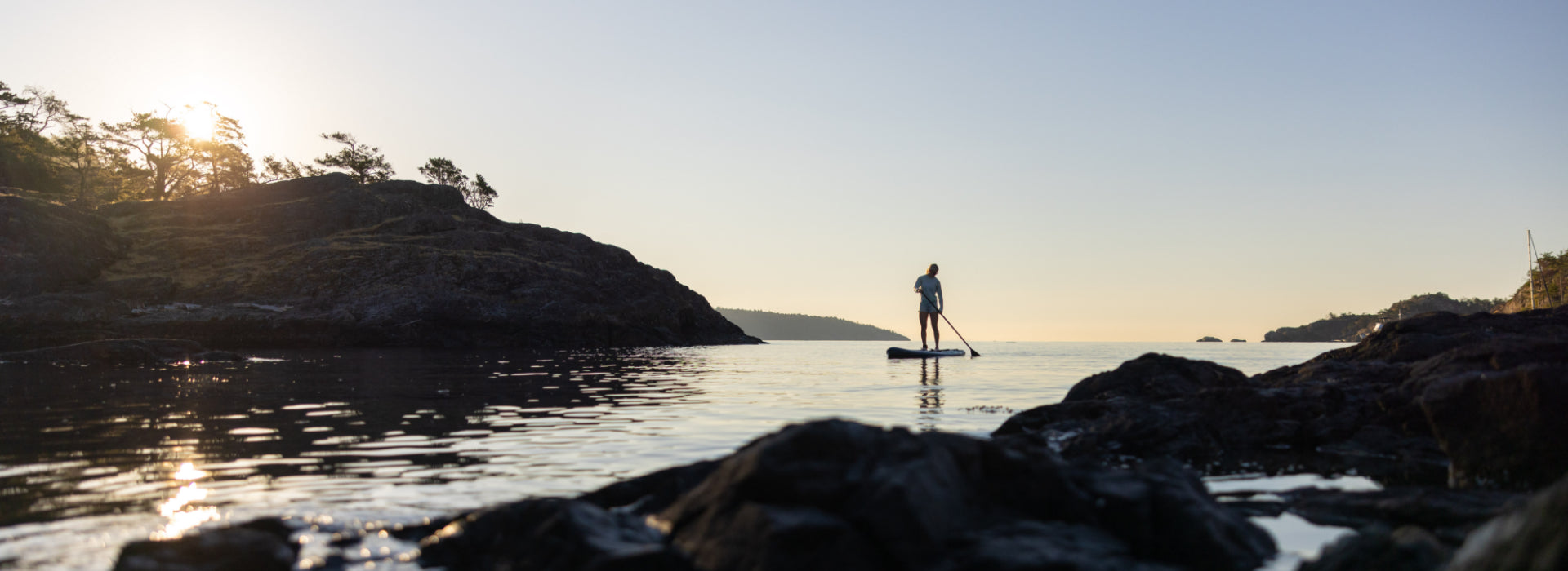 A person paddleboarding out to the ocean during the sunset