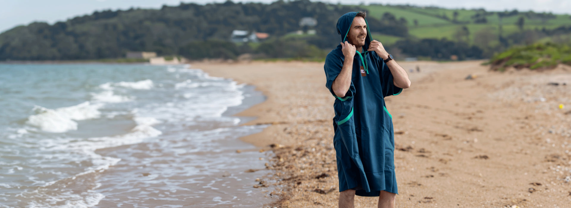 A man wearing the quick change robe on the beach