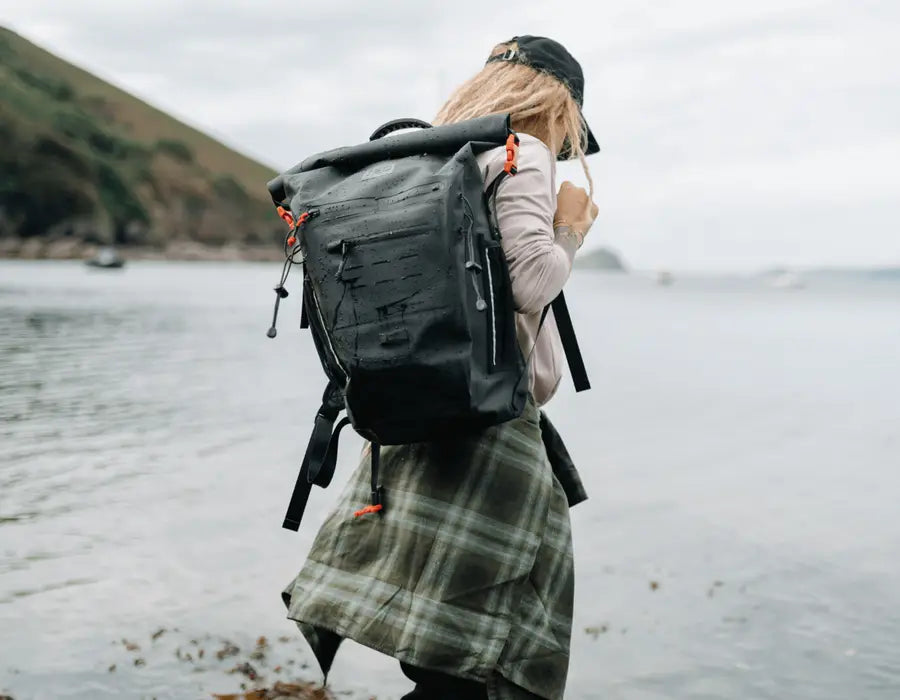 A woman carrying her Red adventure backpack along the beach