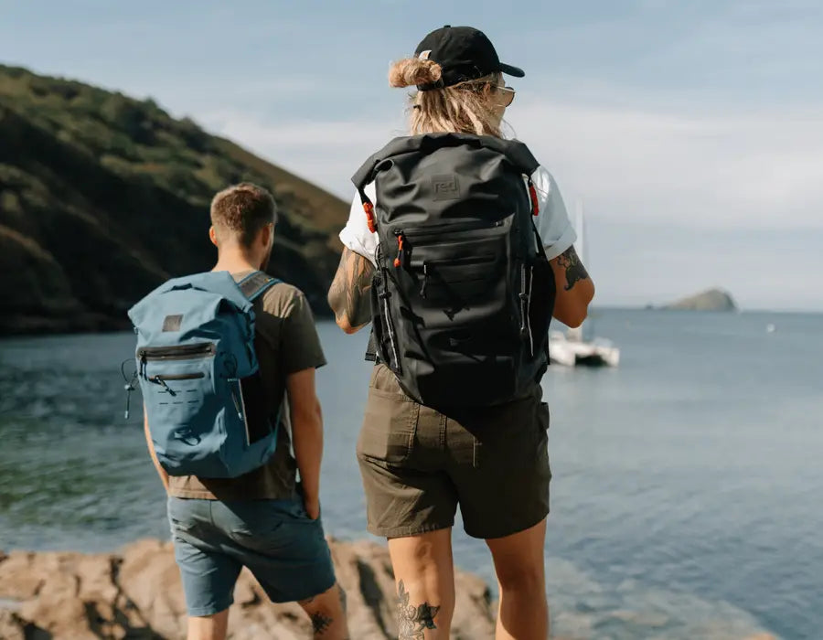 2 people carrying the Red Adventure Backpack , looking out to sea