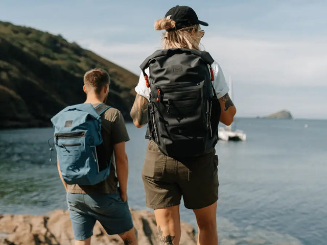 2 people carrying the Red Adventure Backpack , looking out to sea