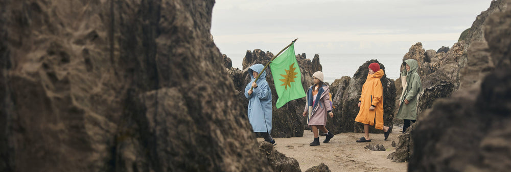 group of children wearing red pro change robe evo robes on the beach