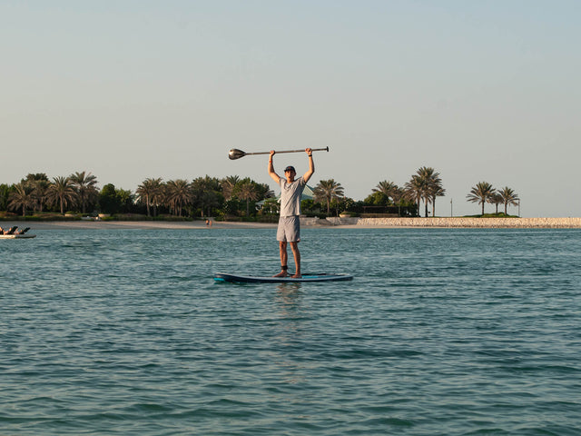 Paddle Boarder In Bahrain With His Paddle Help Over His Head