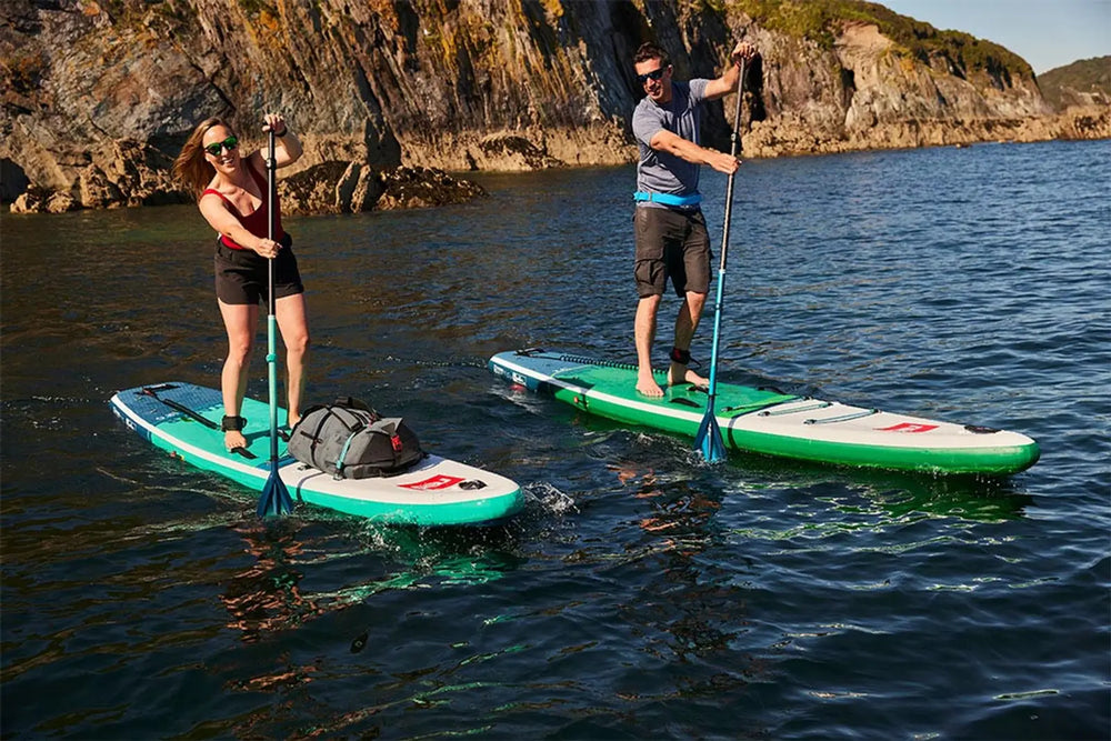 2 people paddleboarding together in the ocean, smiling