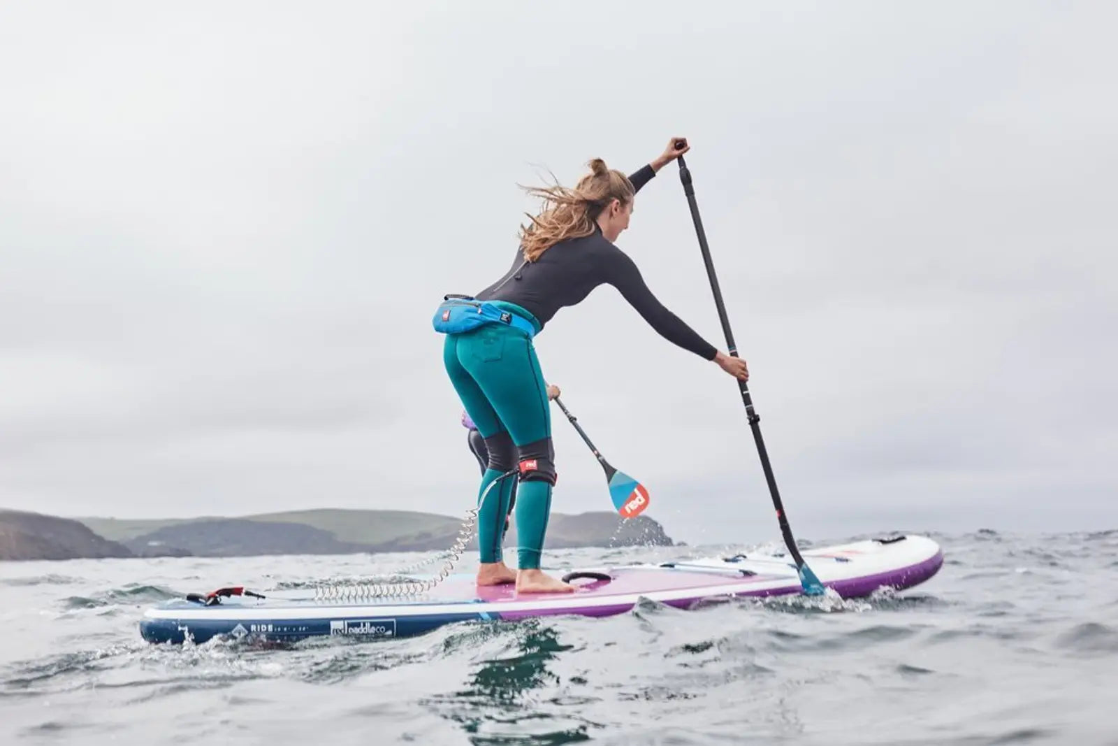 A woman paddleboarding on choppy sea