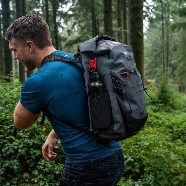 man wearing Red Original Waterproof Backpack in a woodland setting