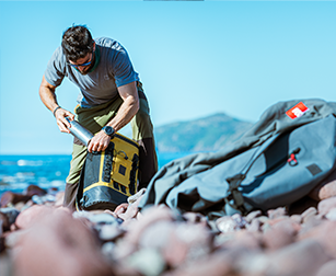 Man putting insulated stainless steel bottle into mustard waterproof cool bag backpack