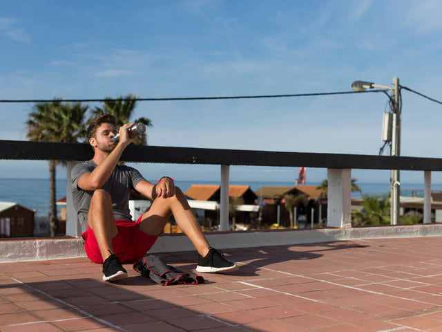 man sitting on the floor drinking from water bottle after run