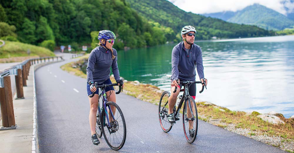 Man and woman cycling by a lake