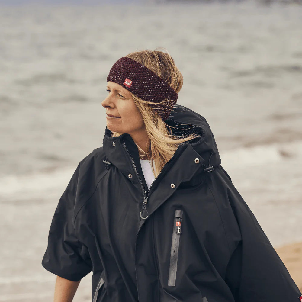 A woman wearing the burgundy merino headband, walking along the beach