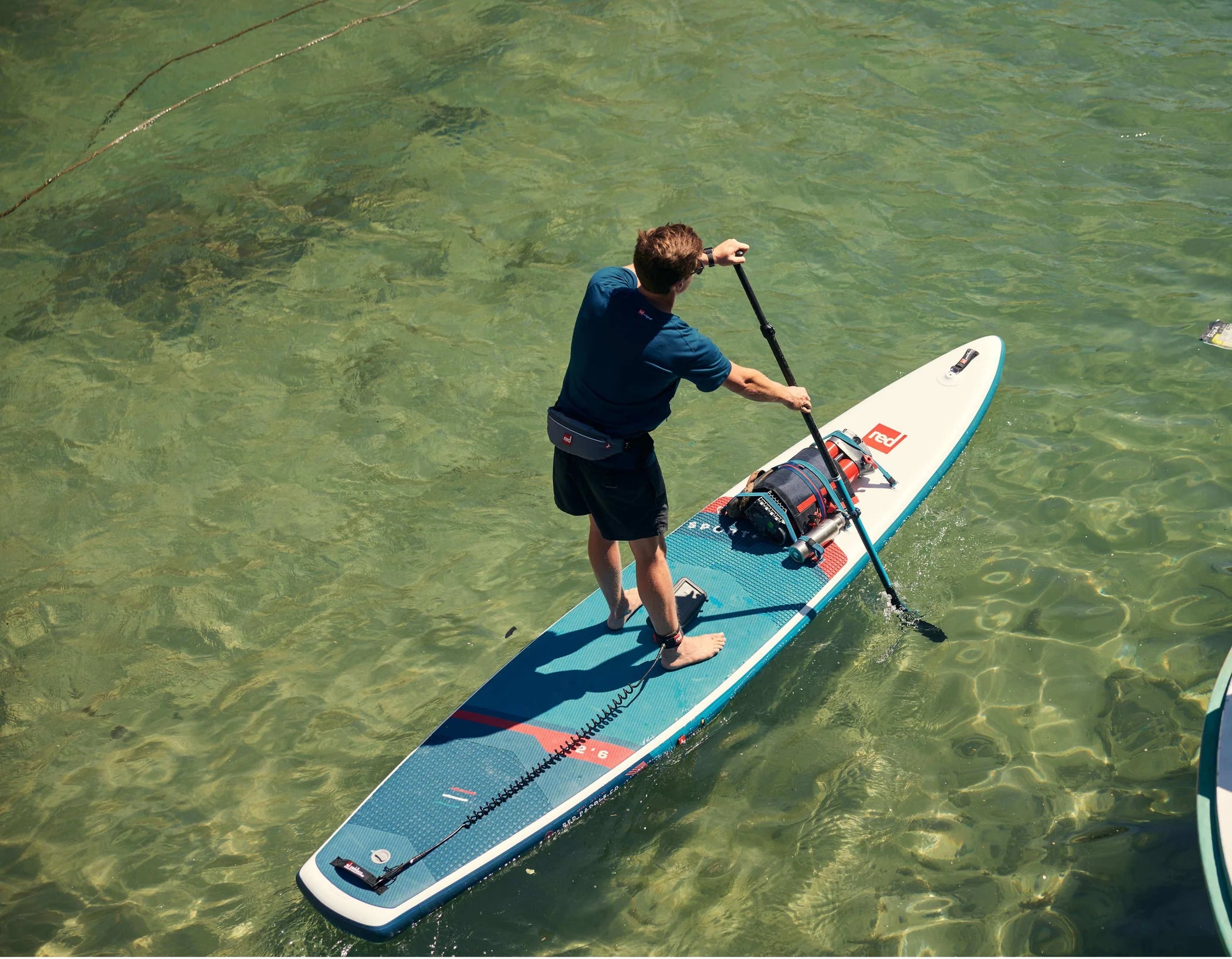 An overview shot of a man paddleboarding on clear water