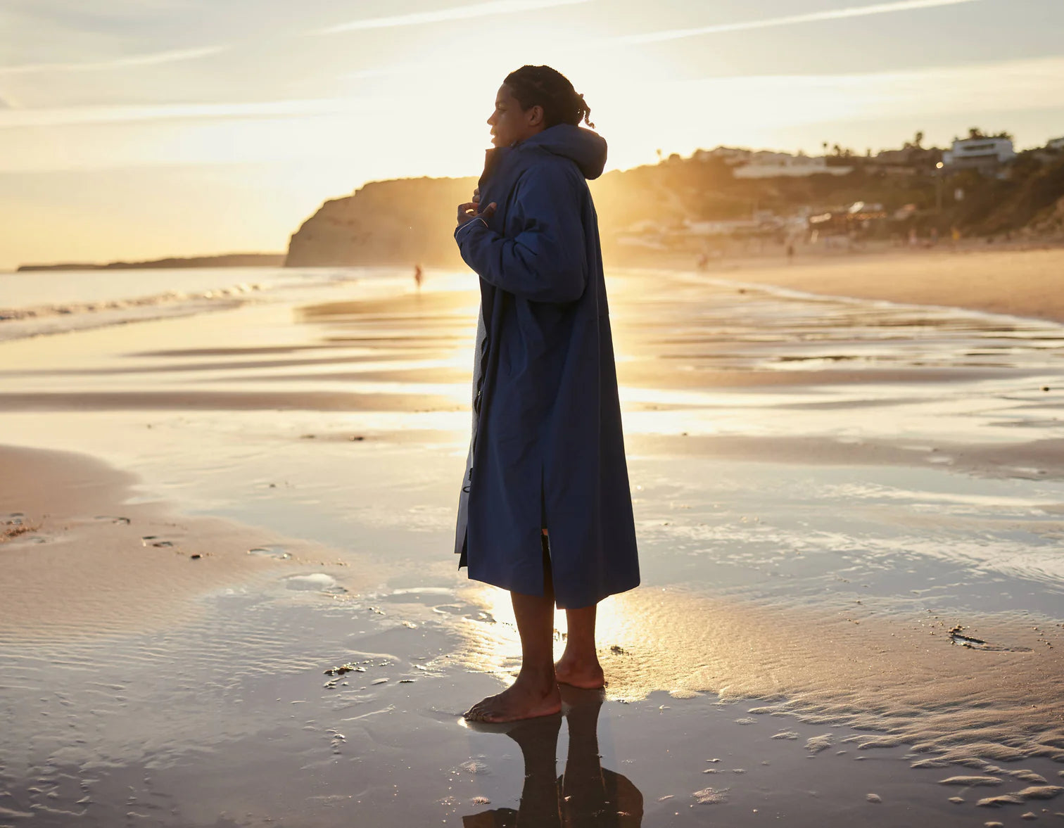 A woman stood on the beach at sunrise wearing the alter evo robe