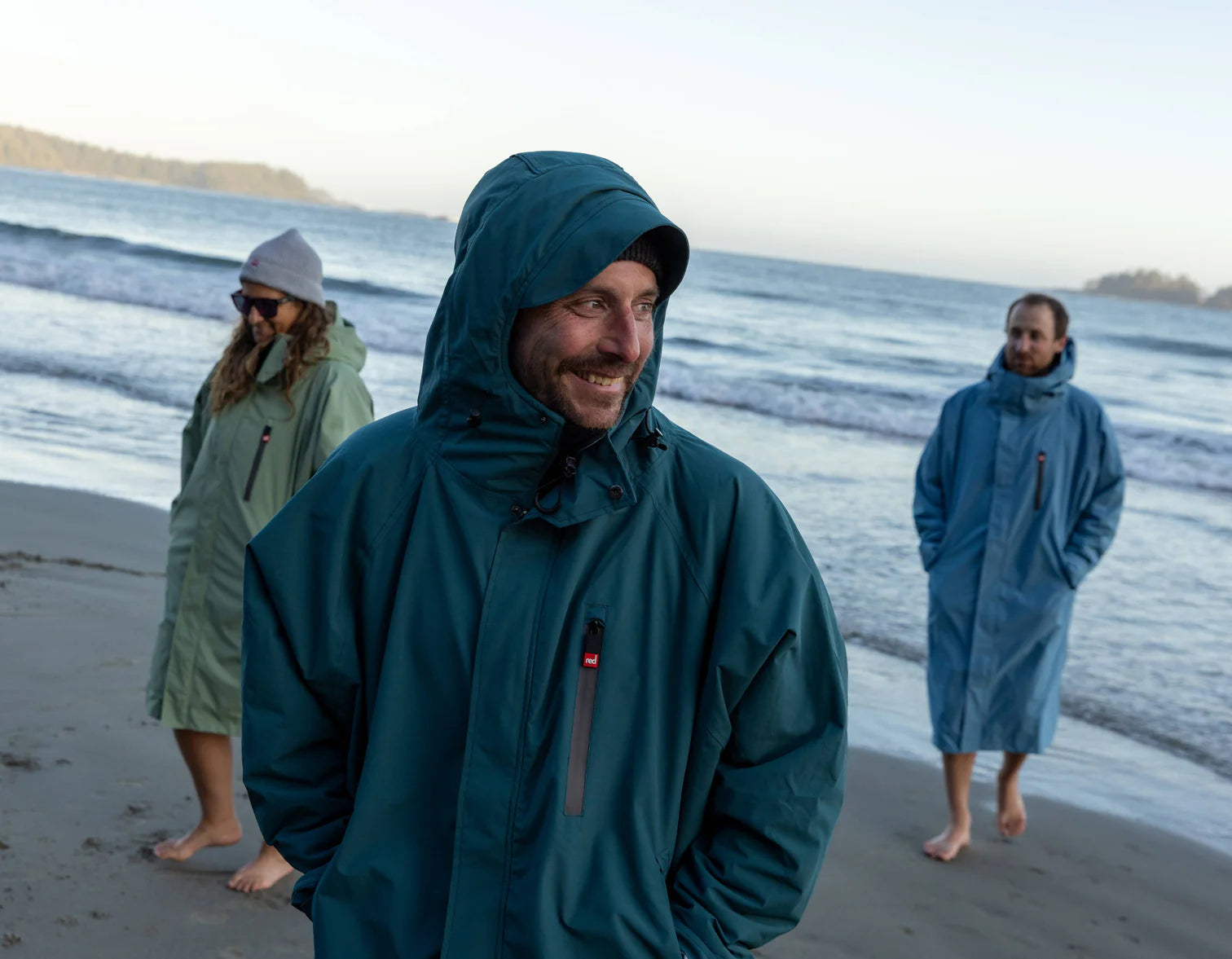 A group of people walking on the beach wearing the alter evo robe