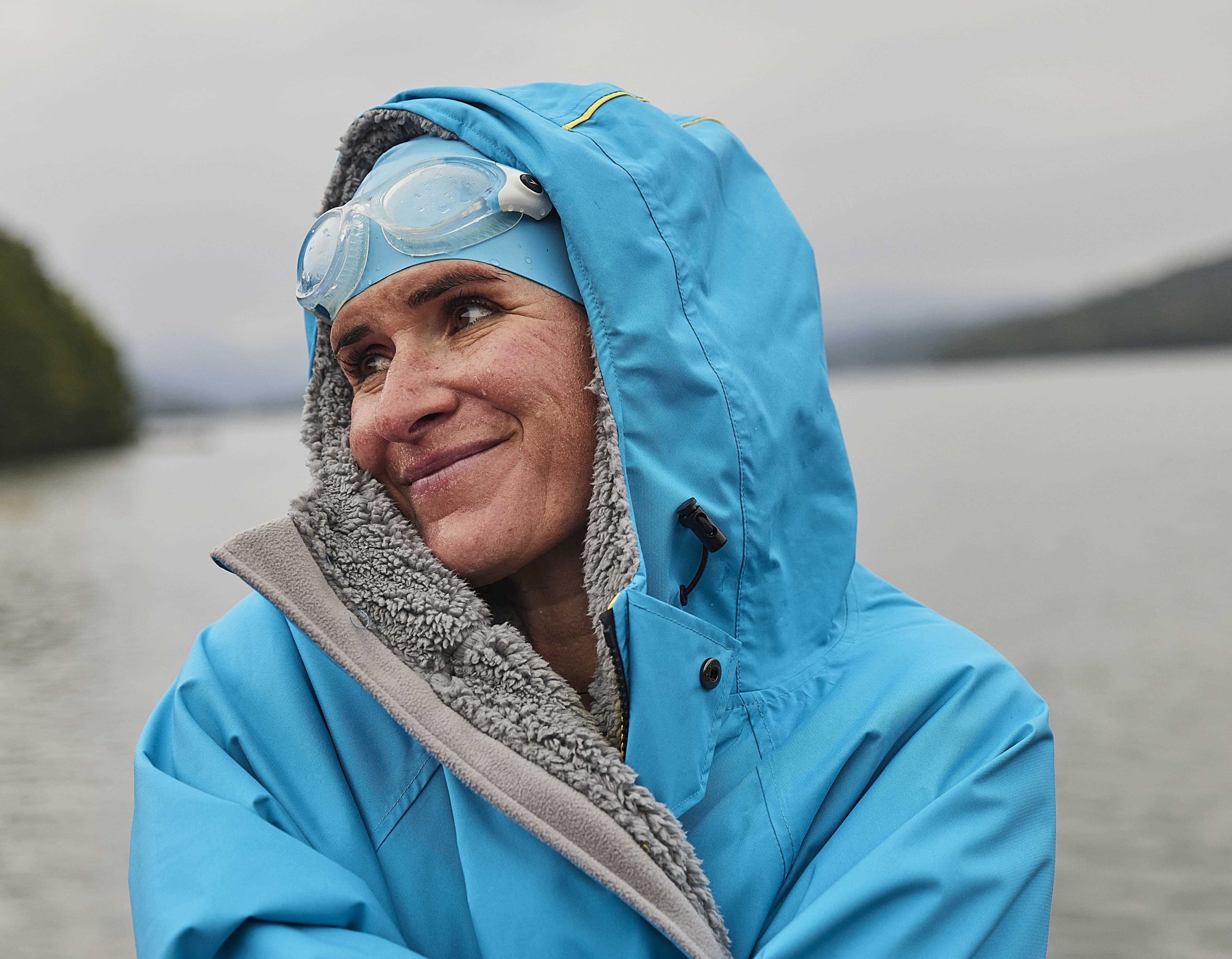 Close up of a female swimmer wearing a Red Long Sleeve Pro Change Evo in Hawaiian Blue at a lake. 