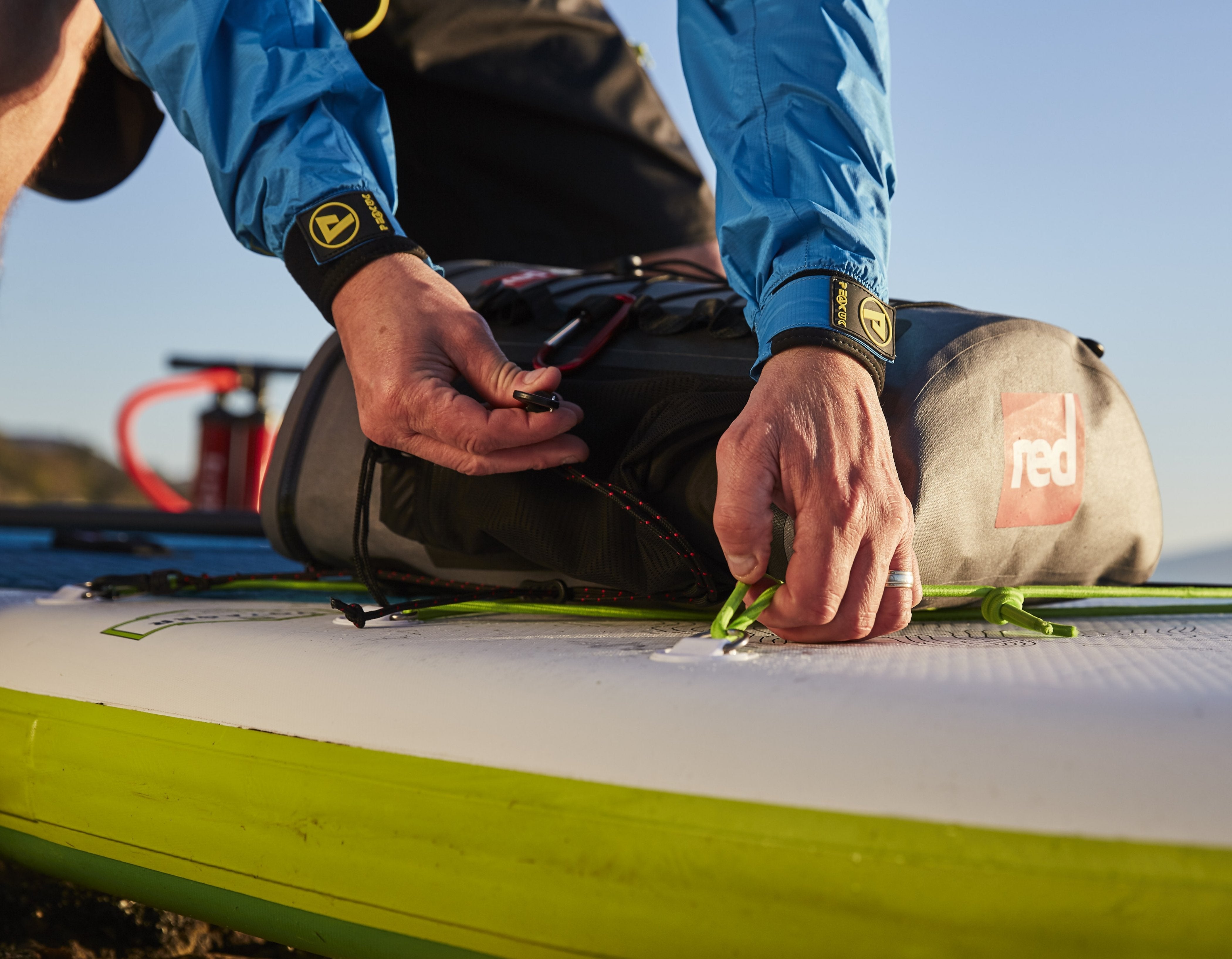 Close up of a Red Deck Bag being attached to a Red paddle board.