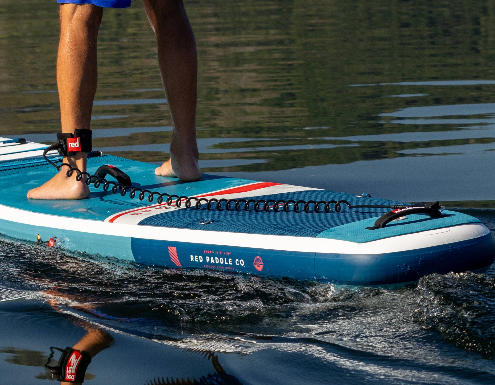 Person standing on a blue paddleboard with visible branding, on a body of water.