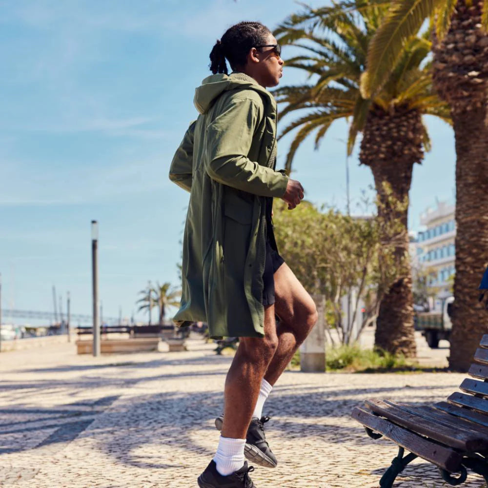 A man jogging on the spot wearing the pursuit lightweight changing robe in olive green